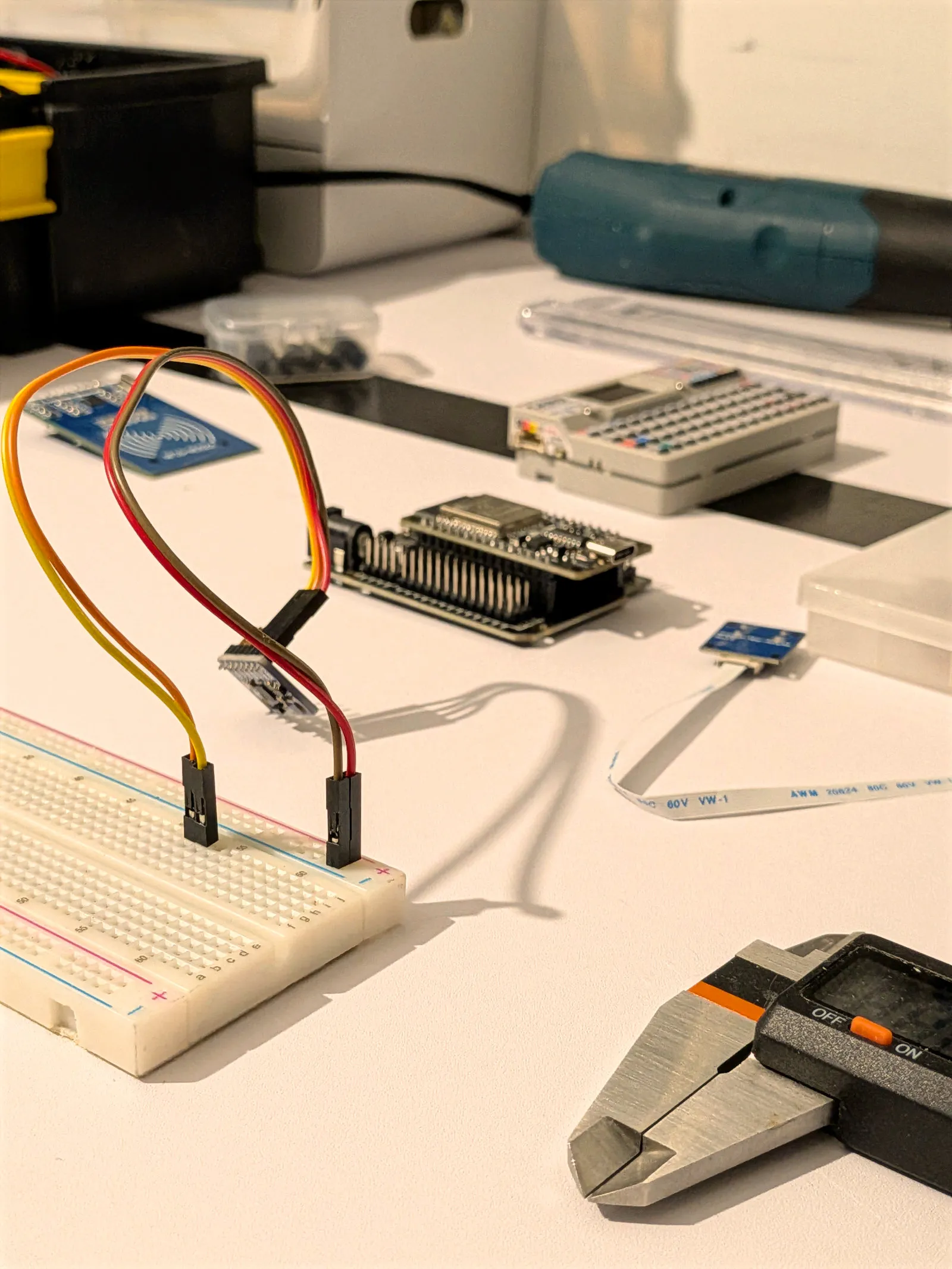The hardware bench: a breadboard wired to a microcontroller, sensor boards and digital calipers laid out on a white surface